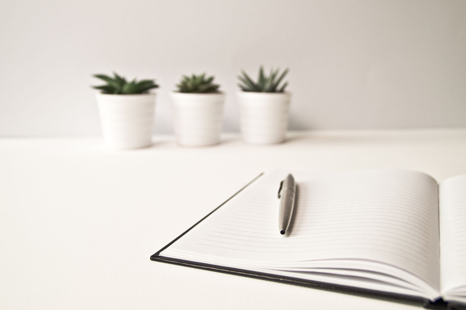 An open notebook and pen on a bright, tidy desk