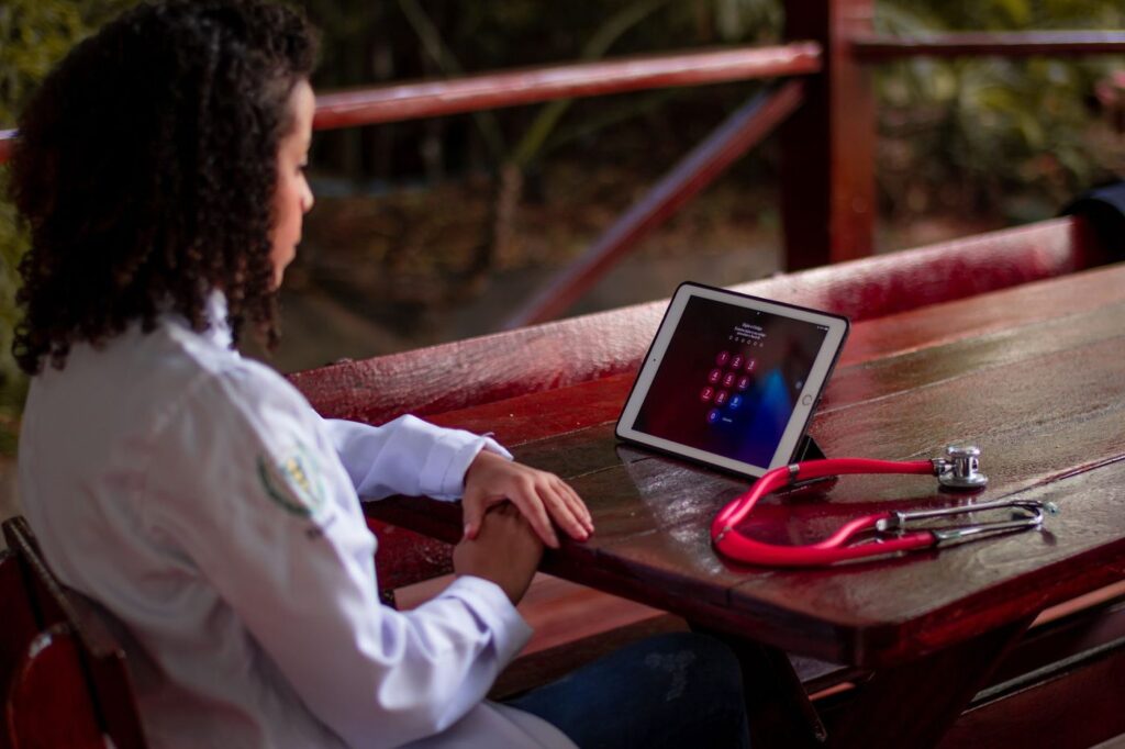 A clinician working on a tablet with a stethoscope on the desk